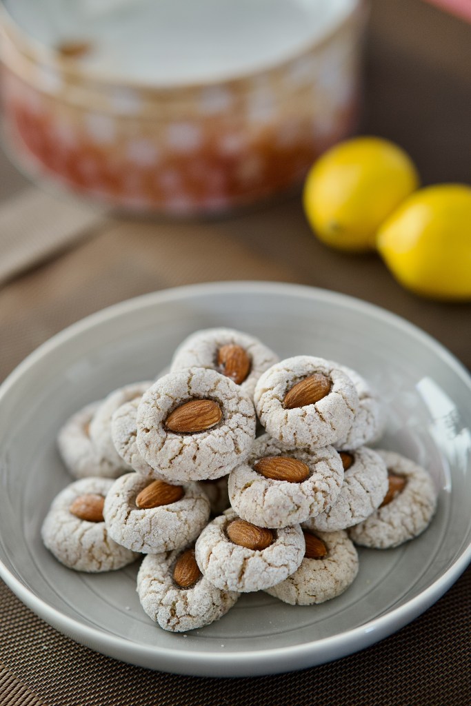 Almond biscuits on a grey plat with lemons in the background.